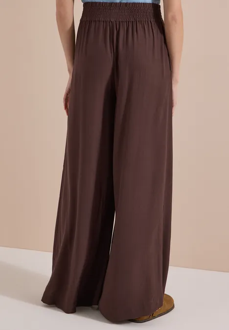 High Waist Wide Leg Hose im Loose Fit brown cacao Rückenansicht einer Person in brauner, weiter Hose mit elastischem Bund, fließendes Material.