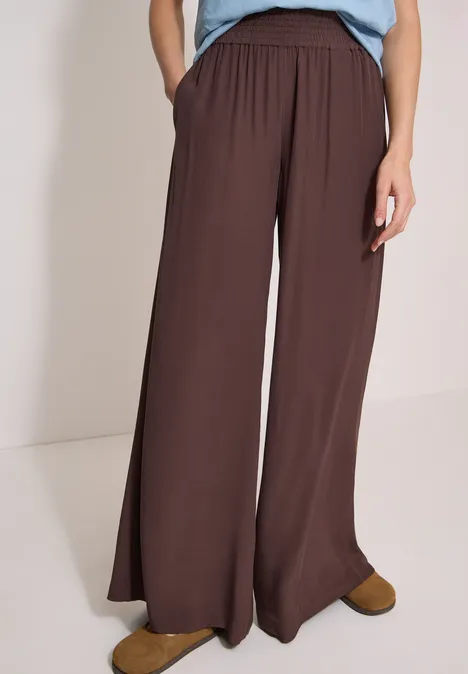 High Waist Wide Leg Hose im Loose Fit brown cacao Braune, weite Hose mit hohem Bund und Taschen, kombiniert mit blauem Oberteil und braunen Schuhen.