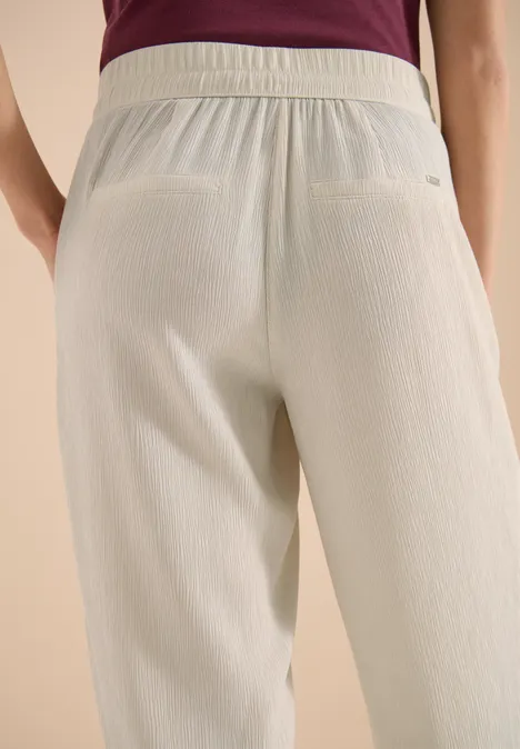 High Waist Straight Leg Hose im Loose Fit grain beige Rückansicht einer Person in hellen, strukturierten Hosen und violettem Oberteil.
