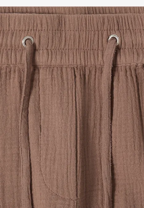 Close-up van de taille van een bruine, gestructureerde broek met elastiek en koord