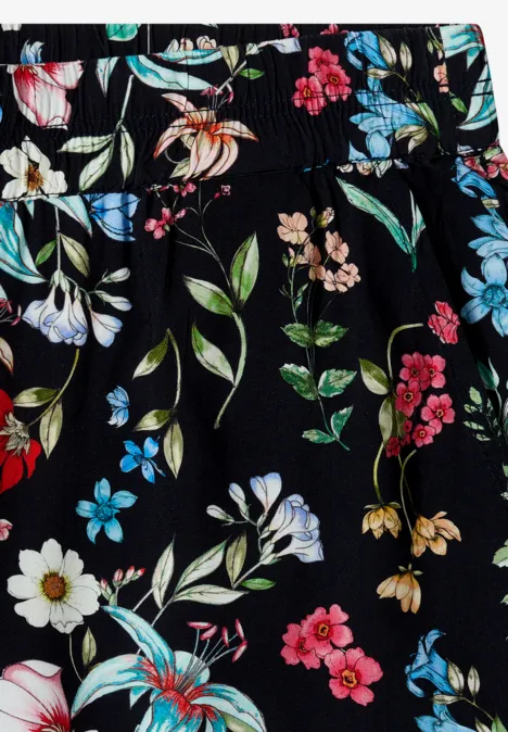 Schwarzer Stoff mit buntem Blumenmuster, weiße, rosa und blaue Blüten sowie grüne Blätter.