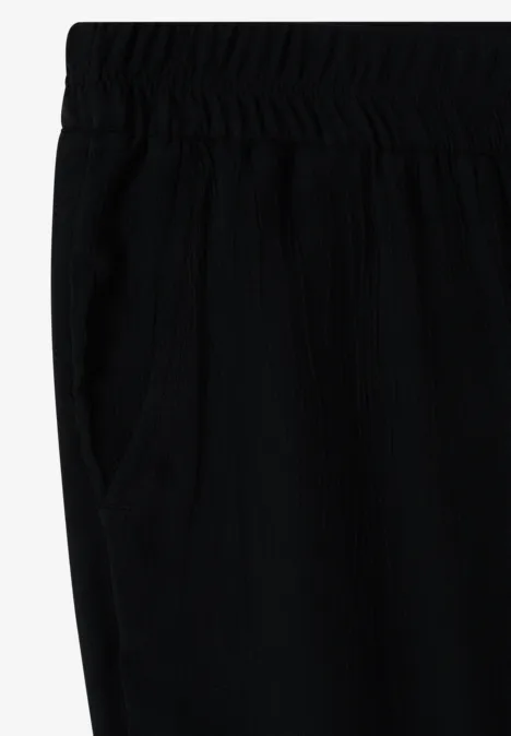 Zwarte, losse broek met elastische taille en zijzak.