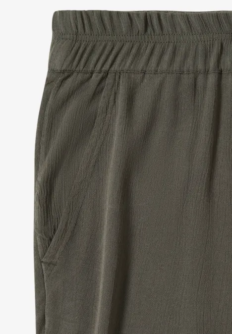Nahaufnahme eines olivgrünen Stoffhosenbeins mit elastischem Bund und seitlicher Tasche.