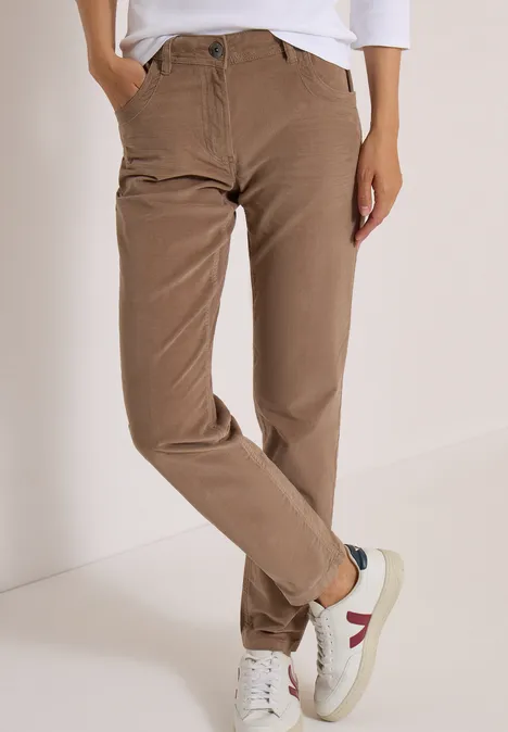 Beige Cordhose mit hoher Taille und weißen Sneakern mit roten Details.