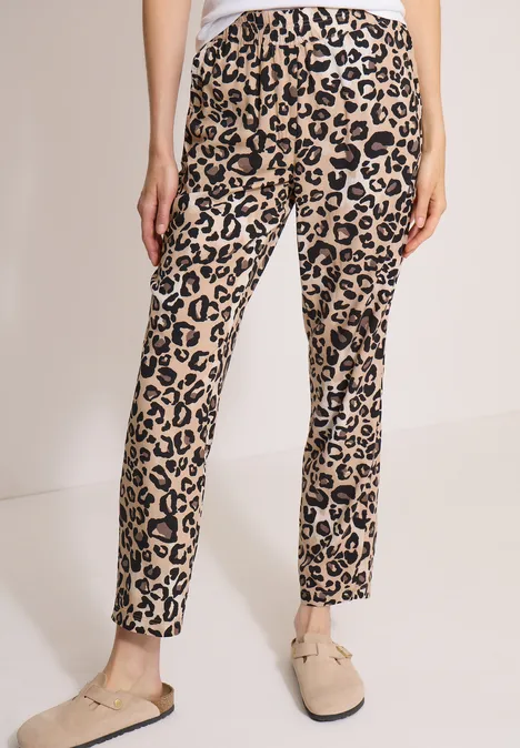Slim Leg Hose im Loose Fit mit Leo-Muster urban taupe Beine in schmal geschnittenen, beige Leopardenmuster-Hosen und beigen Slippers.