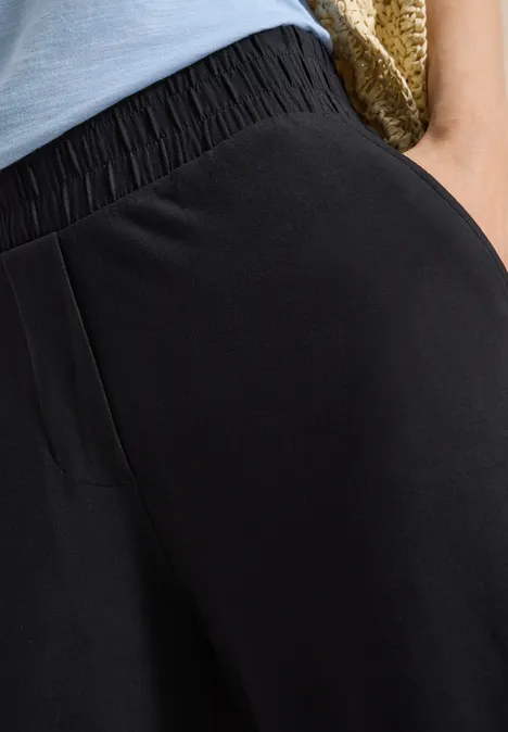 3/4 Wide Leg Hose im Casual Fit Black Nahaufnahme einer schwarzen Hose mit elastischem Bund und Seitentasche.
