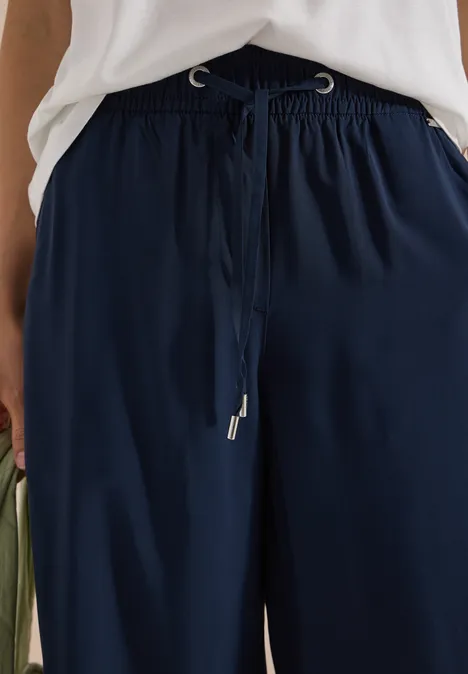 Dunkelblaue, weite Hose mit Kordelzugbund in der Taille, vorne gebunden.
