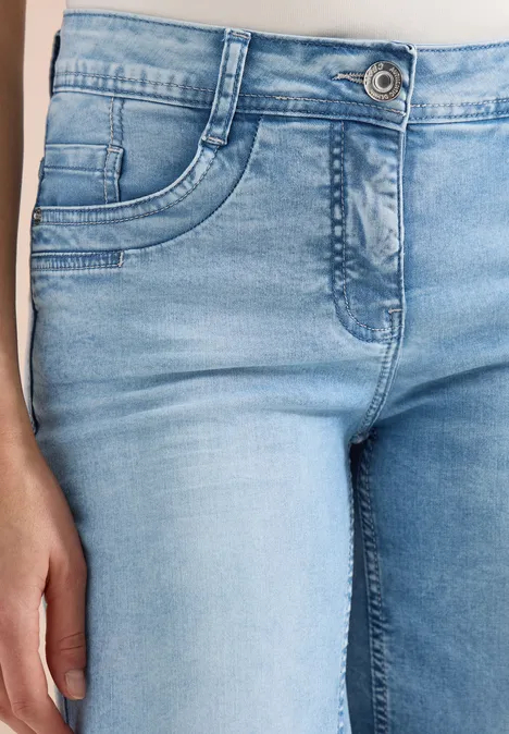 Close-up van een persoon in lichtblauwe jeans, focus op taille en dijen.