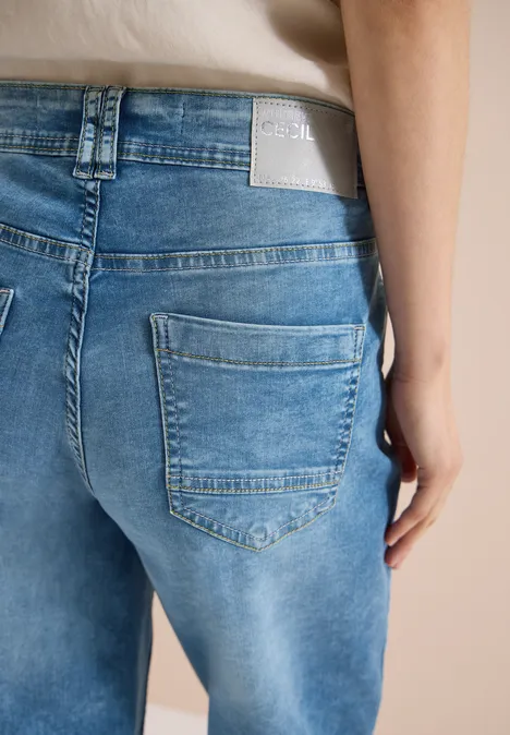 Vue arrière d'une personne portant un jean bleu clair avec poche arrière visible et étiquette.