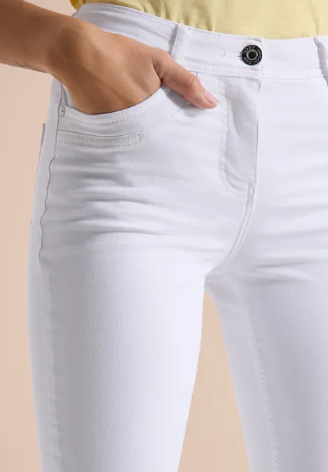 Vrouw in witte, nauwsluitende jeans met steekzak en effen top