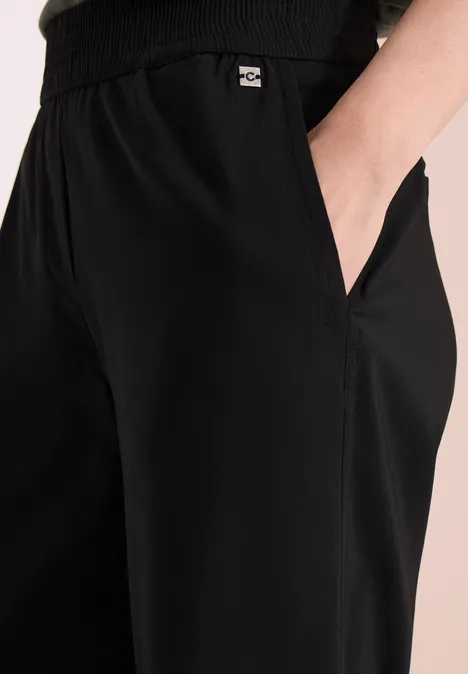 Schwarze Jogginghose mit elastischem Bund und Hand in seitlicher Tasche.