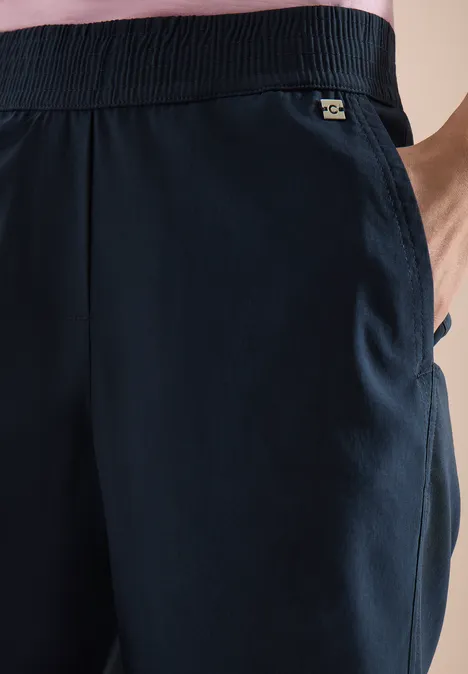 Donkerblauwe, luchtige joggingbroek met elastische taille, zijzak en klein merkembleem.