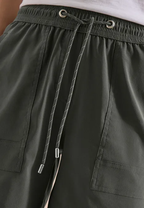 Dunkelgrüne Hose mit elastischem Bund, sichtbarem Tunnelzug und aufgesetzten Taschen