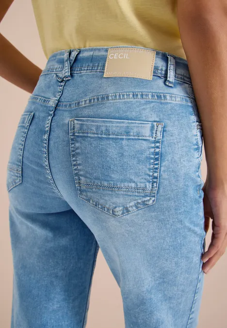 Achteraanzicht van een persoon in lichtblauwe spijkerbroek en geel shirt.