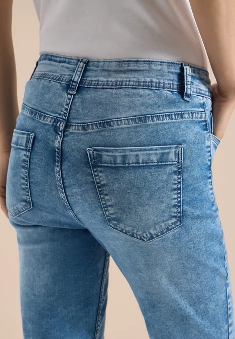High waist Slim Fit Capri Jeans authentic used wash Frau trägt hellblaue Jeans mit sichtbaren Gesäßstaschen und weißem Shirt.
