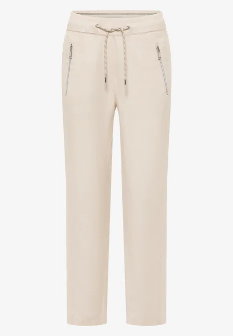 Pantalon beige clair à taille élastique, cordon de serrage et poches zippées latérales.
