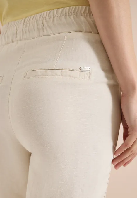 Gros plan sur une personne portant un pantalon beige, focus sur la poche arrière.
