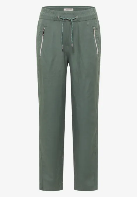 Eine olivgrüne, lässige Hose mit Tunnelzugbund und Reißverschlusstaschen.