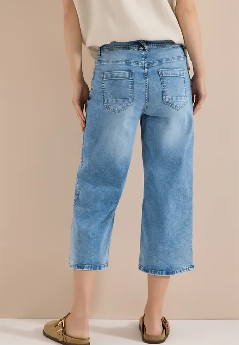 3/4 High Waist Wide Leg Jeans im Slim Fit light blue washed Hintenansicht einer Person in hellblauen, weiten 3/4-Jeans und beigen Slippern.