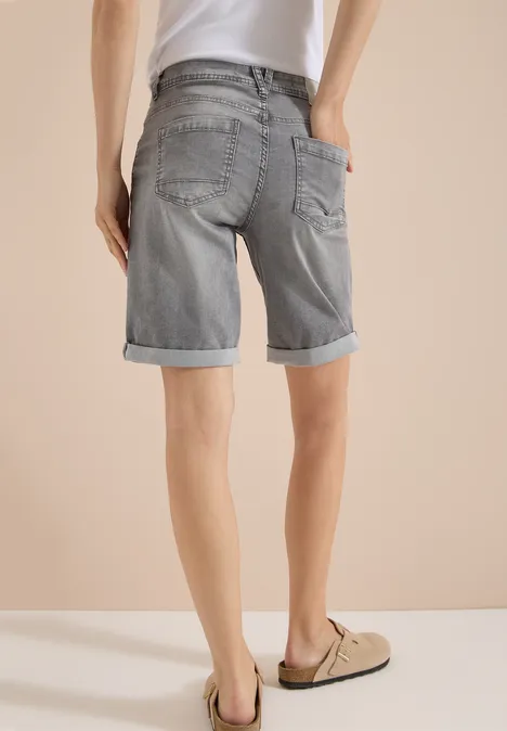 Slim Leg Jeansshorts im Casual Fit mid grey used wash Rückansicht eines Mannes in grauen Jeans-Shorts mit Umschlag und beigen Mokassins vor hellem Hintergrund.