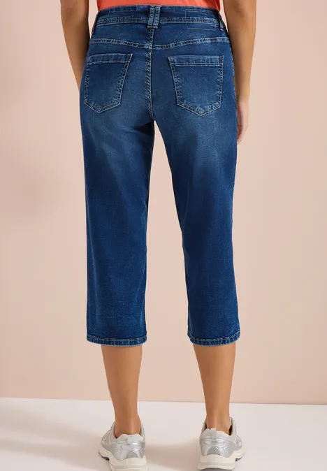 Personne porte un jean capri bleu et des baskets blanches.