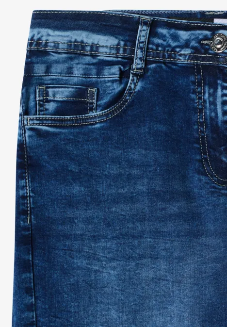 Gros plan sur un jean bleu avec poche avant, passants de ceinture et texture de couture visible.