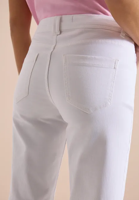 Nahaufnahme eines Gesäßes in weißen Jeans und rosa Oberteil.