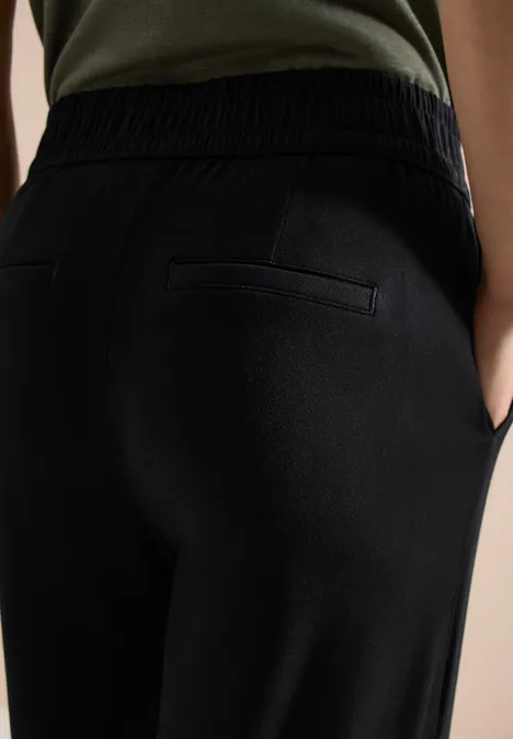 Ansicht eines Rückenteils in schwarzen Jogginghosen mit Gummibund und Gesäßtasche.