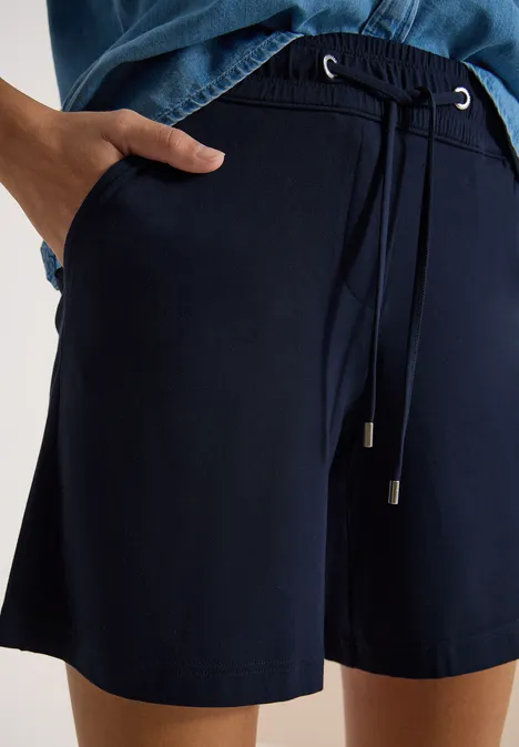 Donkerblauwe shorts met trekkoord en zijzakken, gecombineerd met een bijpassend donkerblauw bovenstuk.
