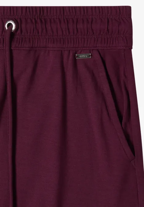 Paarse trainingsbroek met elastische taille, aantrekkoord, zijzak en metalen logo.