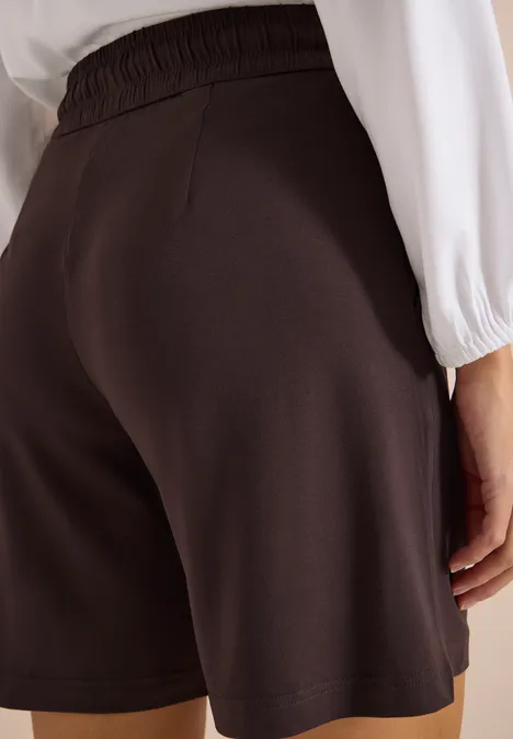 Achteraanzicht van een persoon in losse zwarte short en wit bovenstuk