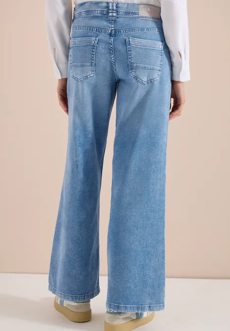 Vue arrière d’une personne portant un jean large taille haute bleu clair sur fond beige