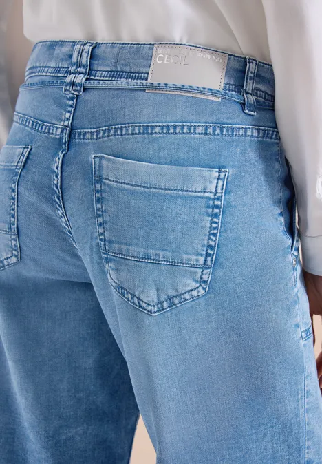 Vue arrière d'une personne portant un jean bleu clair et un haut blanc.