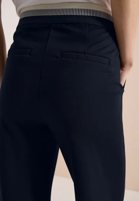 Person von hinten in enger, schwarzer Hose mit gestreiftem Bund.