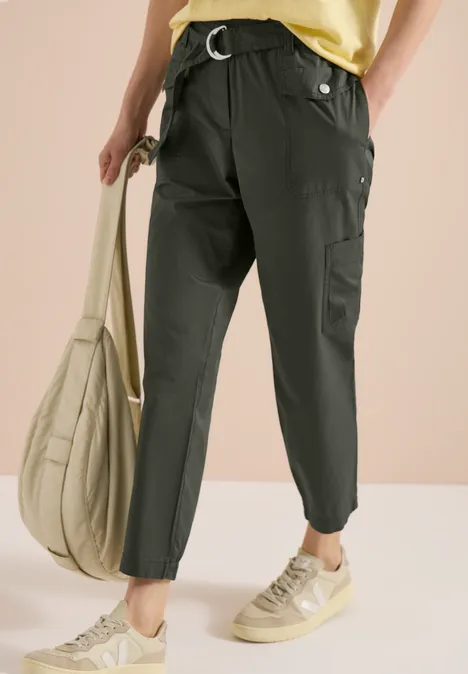 Schlanke olivgrüne Cargohosen, beigefarbene Sneaker und passende Tasche.