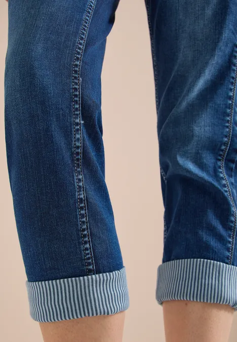 Mid Waist straight leg jeans in casual fit mid blue wash Blauwe spijkerbroek opgerolde zoom bij enkels tegen neutrale achtergrond.