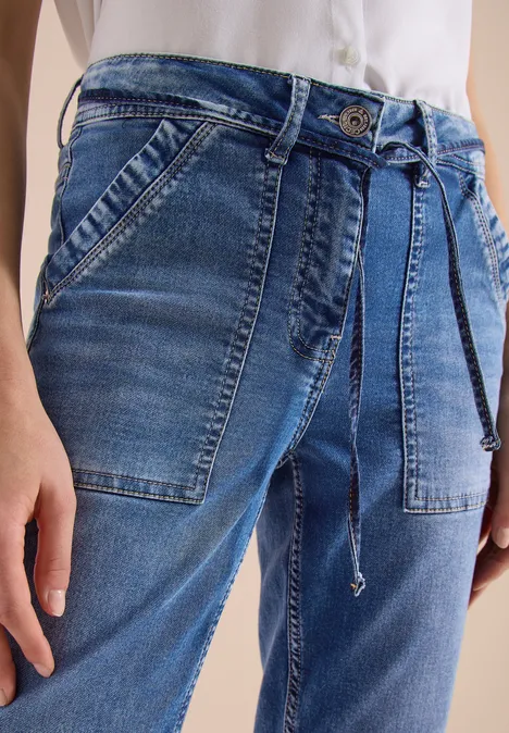 Blaue Jeans mit aufgesetzten Taschen und Kordelgürtel, weiße Bluse