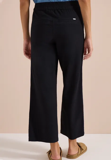 Zwarte, wijde 7/8-broek met elastische taille, achteraanzicht.