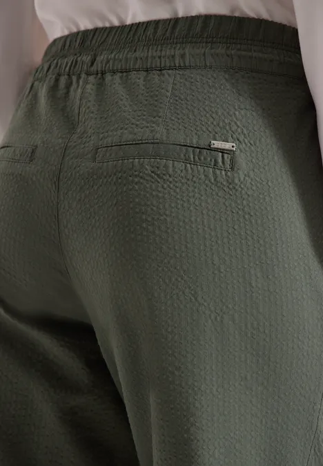 Achteraanzicht van een persoon in een gestructureerde olijfgroene broek met ritszak.