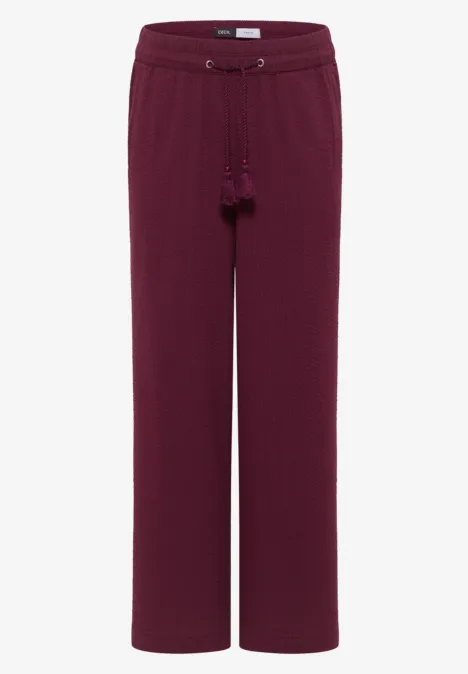 Bordeauxrode damesbroek met wijde pijpen, trekkoord en kwastjes.