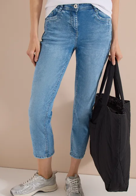 High Waist straight leg jeans in Slim Fit light blue washed Persoon draagt lichtblauwe, enkelhoge jeans, zilverkleurige sneakers en een grote zwarte tas.