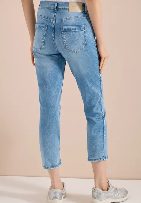 High Waist straight leg jeans in Slim Fit light blue washed Vrouw in lichtblauwe, enkellange, rechte jeans met grijze sneakers tegen neutrale achtergrond.