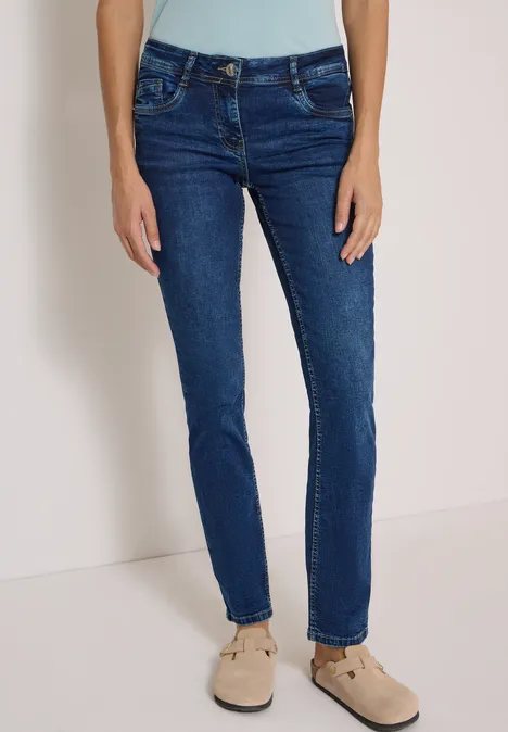 Mid Waist Straight Leg Jeans im Casual Fit mid blue used wash Dunkelblaue Damenjeans in schmaler Passform, getragen mit beigen Loafers.