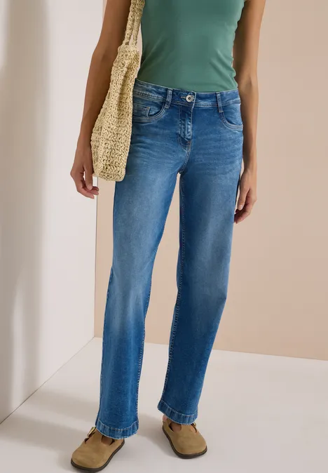 High Waist Wide Leg Jeans im Loose Fit mid blue wash Eine Person trägt ein grünes Top, blaue Jeans und hält eine geflochtene Tasche.