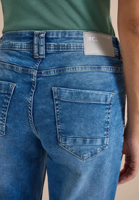 High Waist Wide Leg Jeans im Loose Fit mid blue wash Rückansicht einer Person in blauen Jeans mit aufgesetzten Taschen und grünem Oberteil.