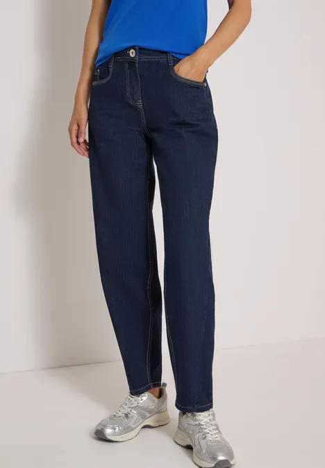 Dunkelblaue, gerade geschnittene Jeans mit Hosentaschen, kombiniert mit silbernen Sneakers.