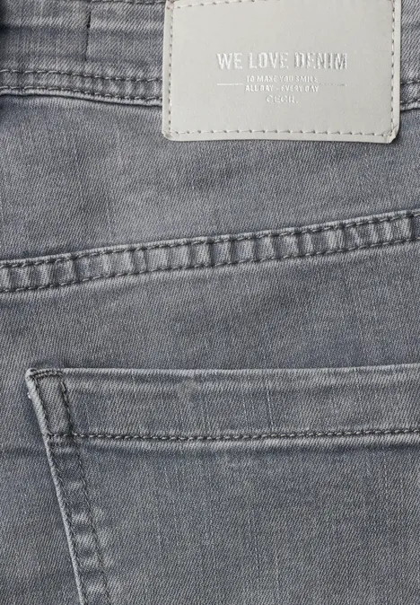 Nahaufnahme einer grauen Jeans mit Lederetikett 'WE LOVE DENIM' über der Tasche.