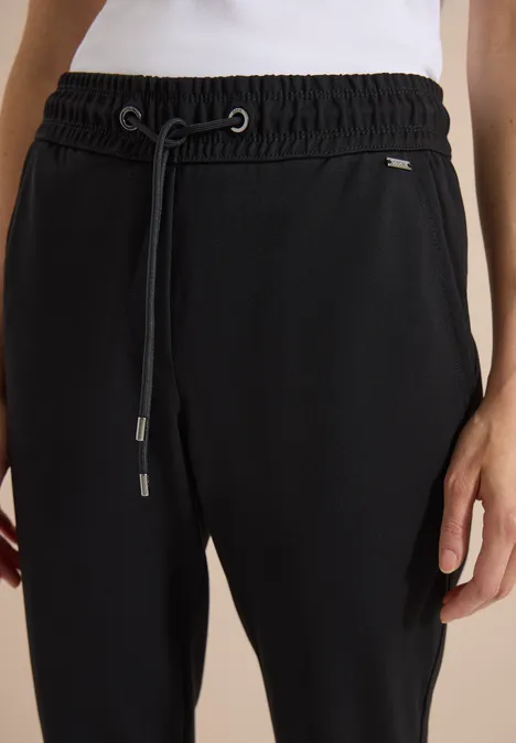 Zwarte, aansluitende joggingsbroek met elastische taille en trekkoord, gecombineerd met een wit shirt.