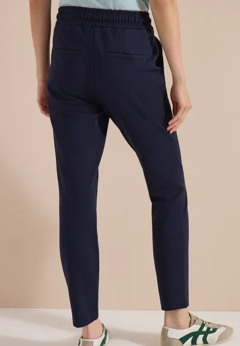 Donkerblauwe, slim fit joggingbroek met elastische taille en zakken, van achteren gefotografeerd.