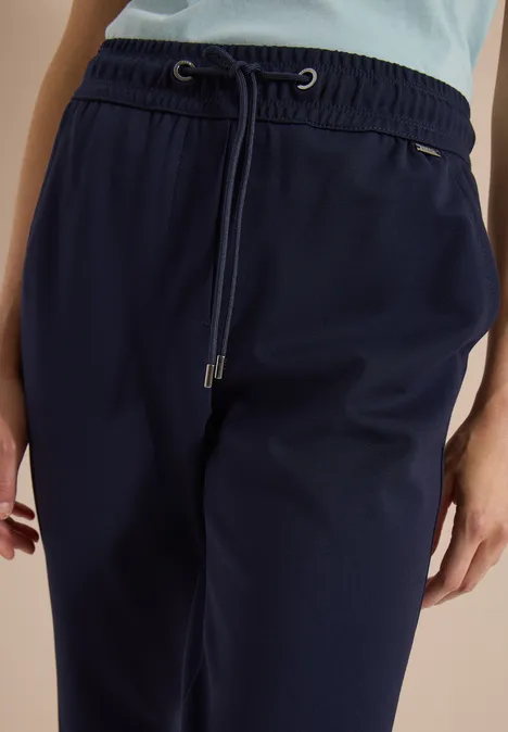 Close-up van een donkerblauwe joggingbroek met trekkoord en hoge taille.